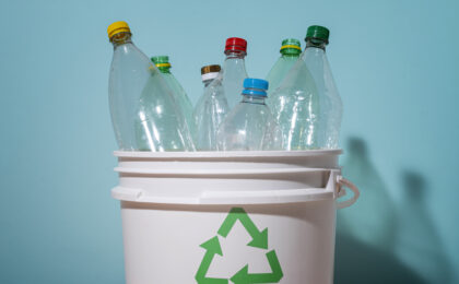 Puste plastikowe butelki w koszu z logiem recyclingu