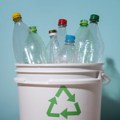 Puste plastikowe butelki w koszu z logiem recyclingu