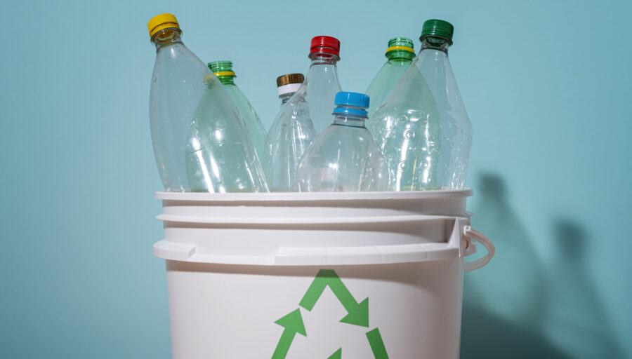 Puste plastikowe butelki w koszu z logiem recyclingu